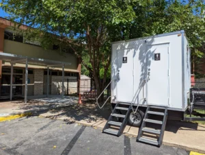 Two-stall restroom trailer with women's and men's rooms outside a campus building