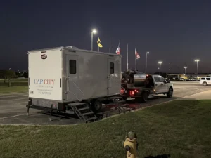 Cap City Rentals restroom trailer hitched to a service truck for evening delivery