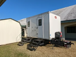 Two-station restroom trailer with women's and men's doors and an on-board generator