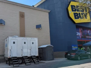 Restroom trailer and ADA-certified portable unit outside a retail store during renovation